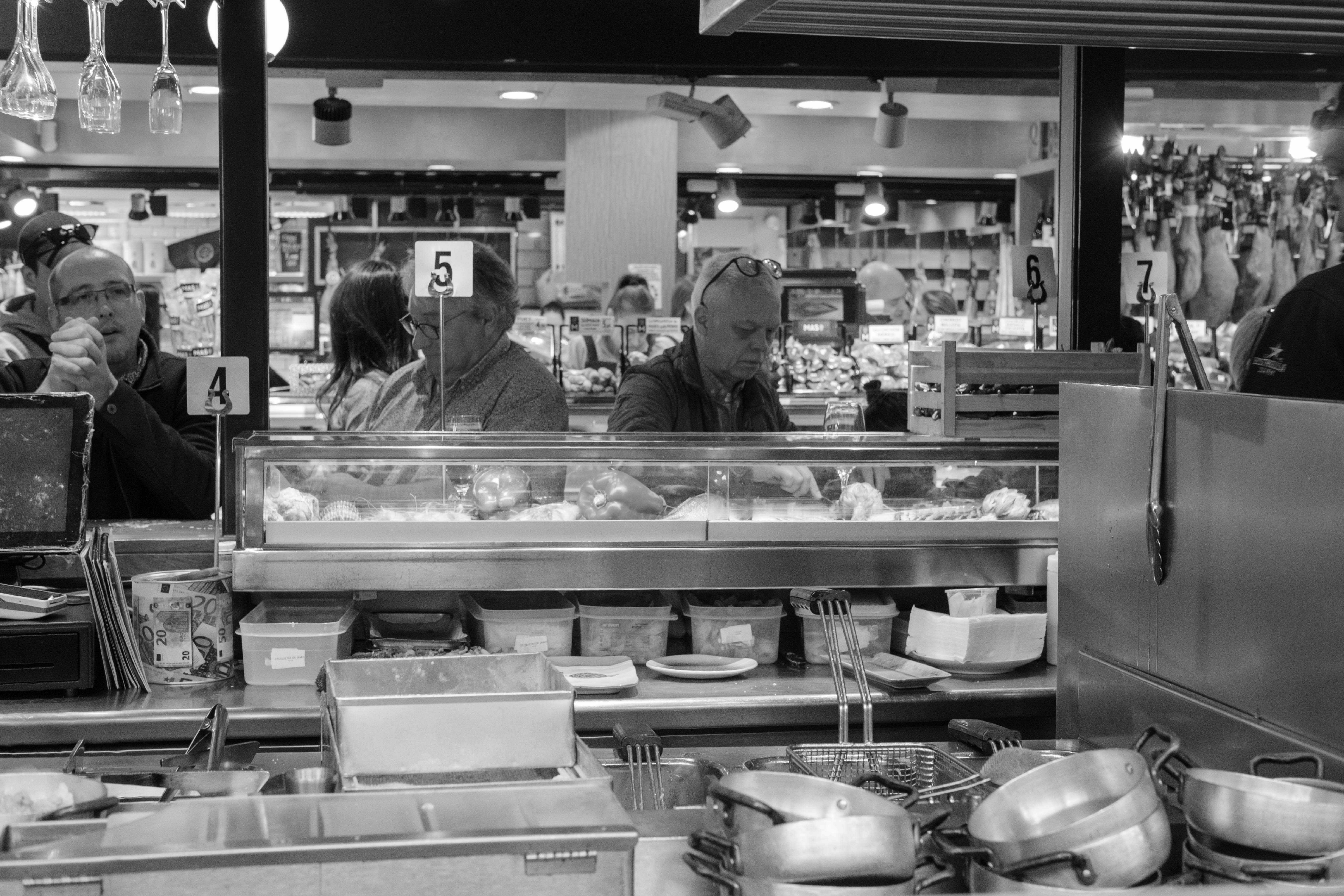 A bustling restaurant kitchen, with a chef preparing food amidst pots, pans, and ingredients.