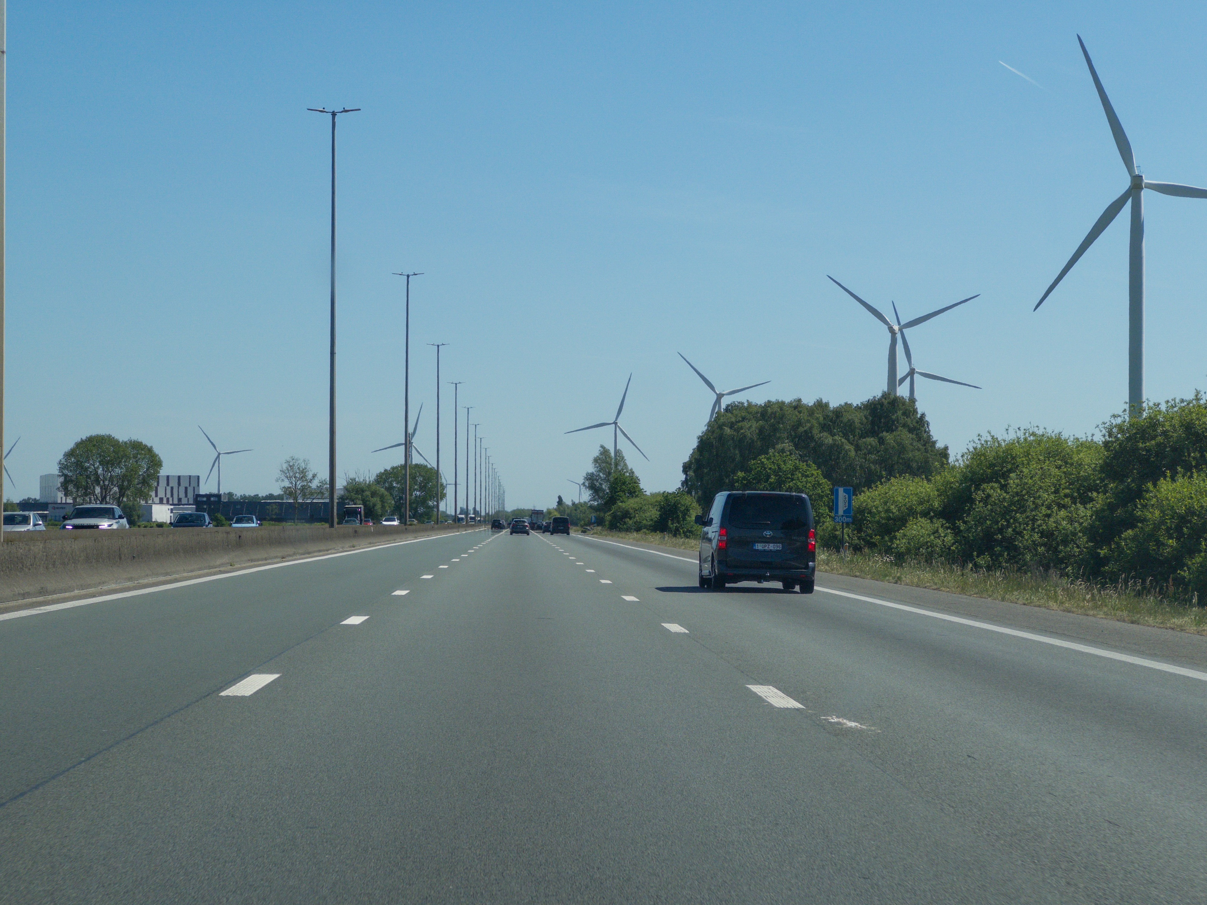 A highway lined with wind turbines under a clear blue sky.
