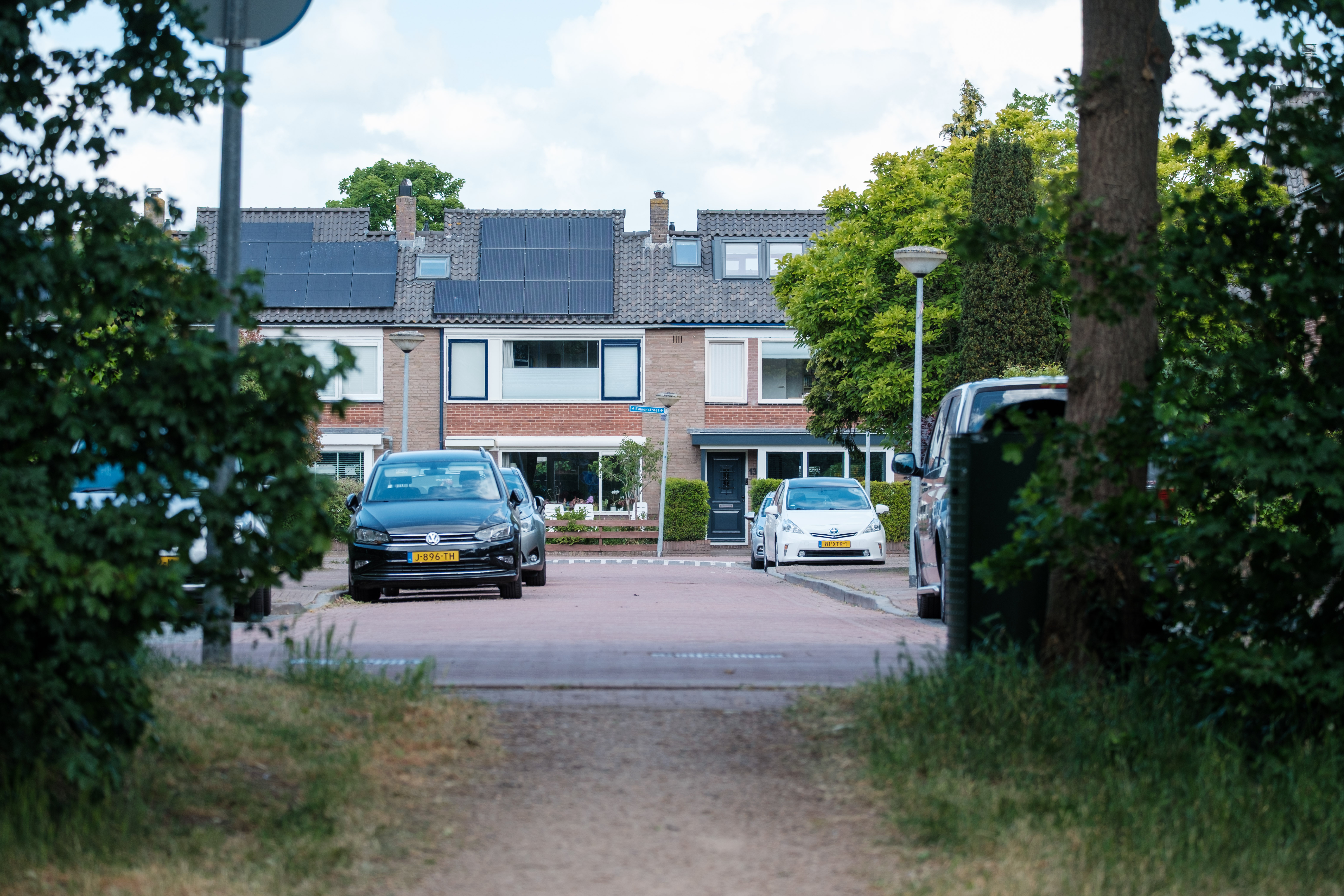 A residential street with parked cars and houses in Huizen, Netherlands.