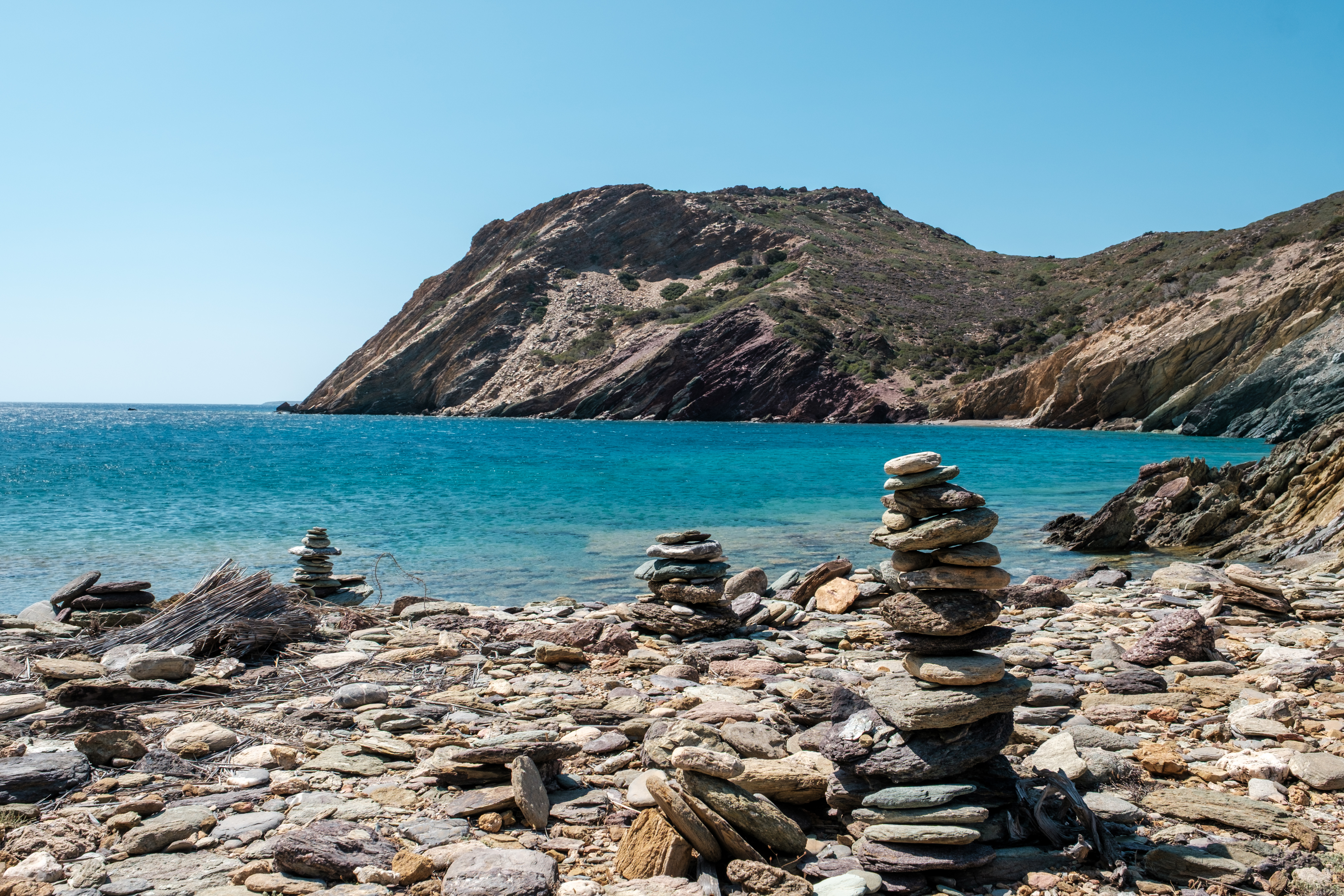 Stacks of rocks by a turquoise sea with a rocky hill in the background, Palaikastro, Crete.