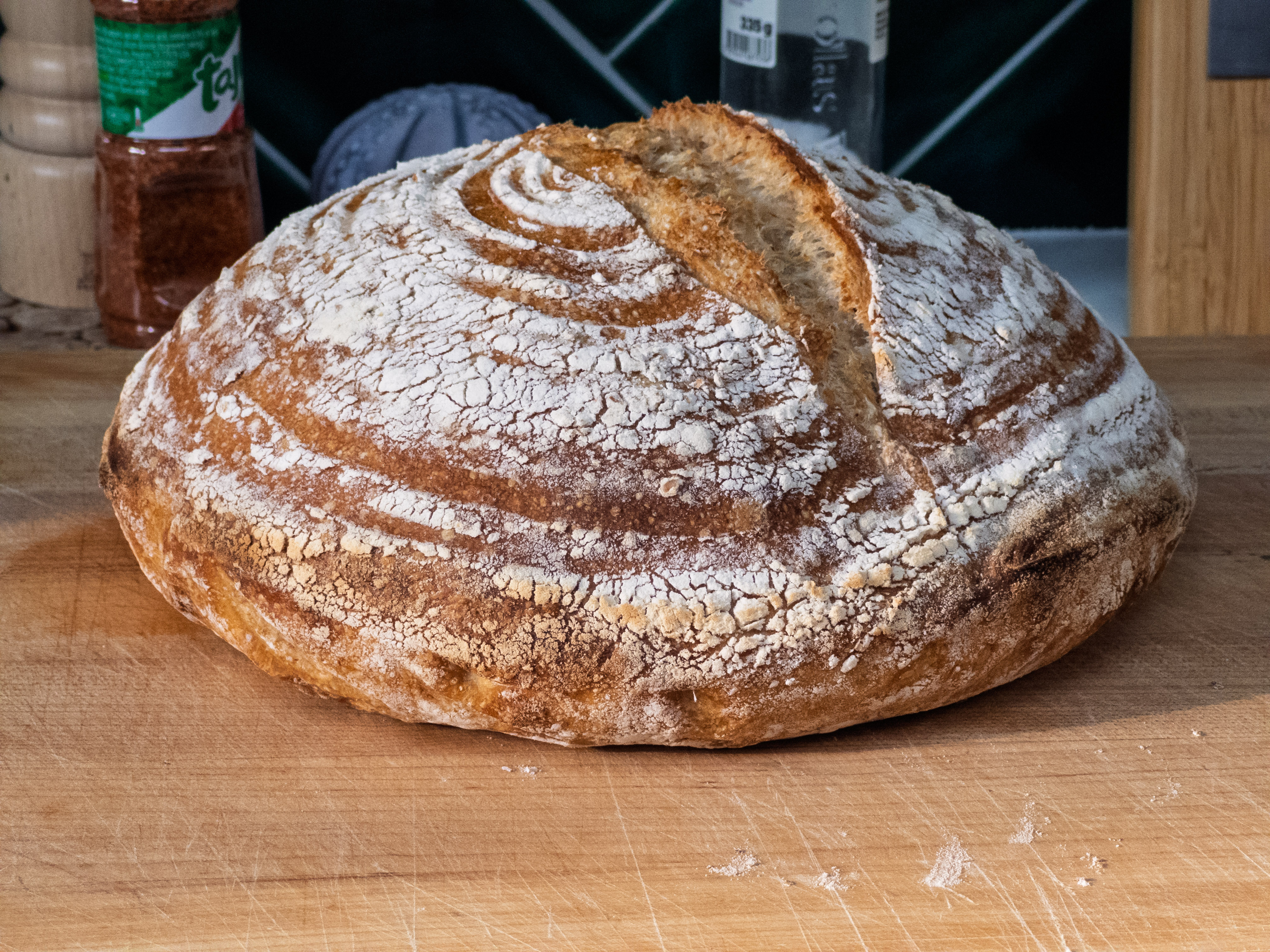 A freshly baked round loaf of crusty bread on a wooden cutting board.