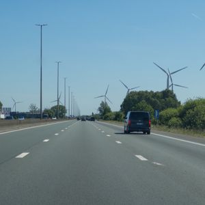 A highway lined with wind turbines under a clear blue sky.