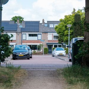 A residential street with parked cars and houses in Huizen, Netherlands.