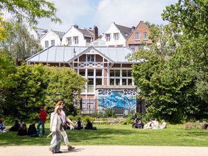 People relaxing on the grass near a building with graffiti in Vondelpark, Amsterdam.