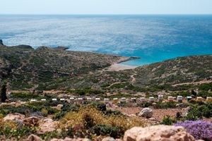 Beehives dot a rocky hillside overlooking the turquoise sea in Παλαίκαστρο, Crete.