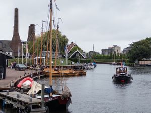 Boats docked and sailing in Gemeentelijke Jachthaven Huizen, Netherlands, with people walking along the quay.